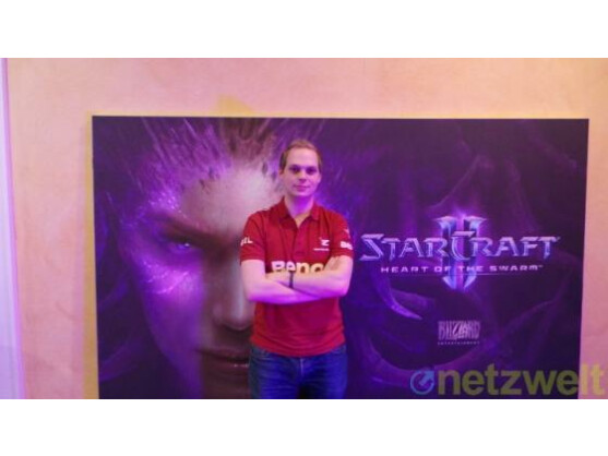 Dennis "mouzHasuObs" Schneider vor einem Starcraft 2: Heart of the Swarm-Plakat.