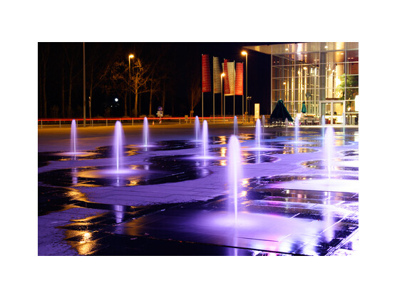 Am Abend geht an unzähligen Stellen in der Stadt das Licht an. Viele Gebäude sind, sobald es dunkel wird, effektvoll beleuchtet. Diese Wasserspiele gibt es im Sommer vor den Gebäuden von T-Com in Bonn zu bewundern. Ein Stativ und eine lange Verschlusszeit liefern dieses Ergebnis - Belichtungszeit drei Sekunden.