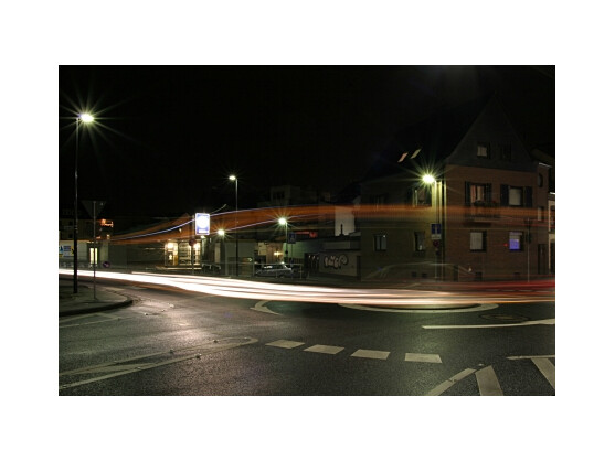 An einem Kreisverkehr bei Nacht ist manchmal ein wenig Wartezeit angesagt, bis endlich ein Auto vorbeifährt. Das Beispielbild hat einen Bus und zwei Autos in einem Bild eingefangen. 15 Sekunden Belichtungszeit und ein bisschen Glück, dass mehrere Fahrzeuge nacheinander durchs Bild fuhren, waren dafür nötig. Wie die Sterne um die Lampen herum entstehen, wird später noch beschrieben.