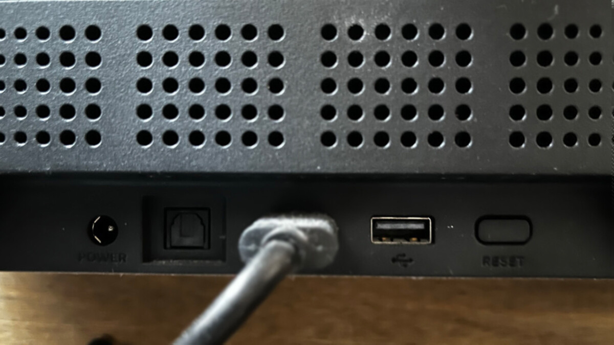 En la parte posterior del Roku Streambar hay puertos HDMI, USB y ópticos.  Hay casquillos roscados para el montaje en la pared a la derecha y a la izquierda del hueco para las conexiones.